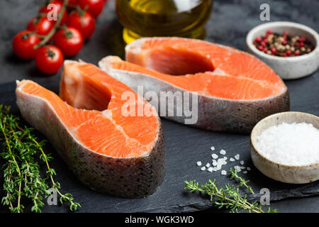 Due bistecca di salmone bistecche e spezie su nero ardesia sfondo. Primo piano. Cibo sano e pulito il concetto di mangiare Foto Stock