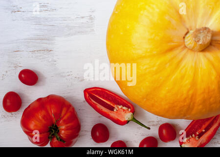 Vista piana. Grande zucca, big red pomodoro, a fette peperone rosso e pomodorini su uno sfondo luminoso. Adatto per decorare il menu di ristoranti. V Foto Stock