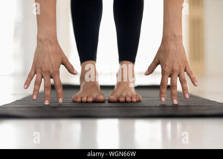 Donna pratica lo yoga, uttanasana pongono, mani e piedi da vicino Foto Stock