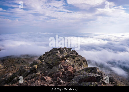 Peñalara picco, nella Sierra de Guadarrama, visto dalla scogliera di uccelli e di garofani, un giorno di nuvole. Foto Stock