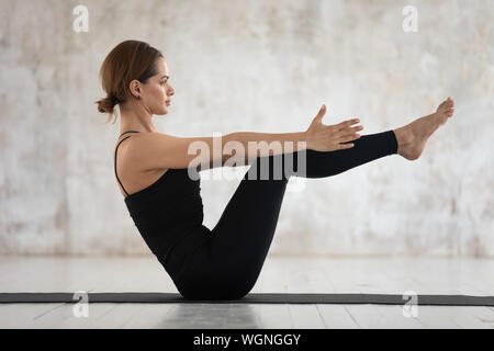 Giovane donna a praticare yoga, facendo Paripurna Navasana esercizio Foto Stock