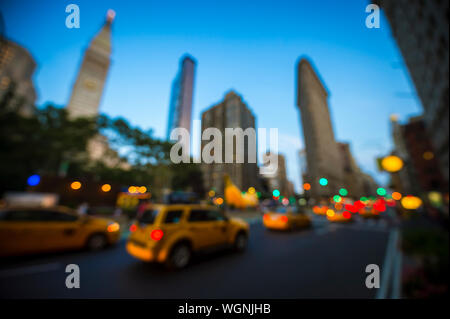 Serata di defocus vista del traffico urbano luci su strade di città con grattacieli contro il cielo blu sulla Fifth Avenue a Manhattan, New York City, Stati Uniti d'America Foto Stock