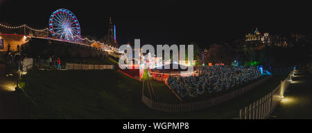 EDIMBURGO, SCOZIA 13 DICEMBRE 2018: Vista panoramica della fiera di Natale illuminata con un sacco di merchandising decorazione brillante e ruota della fortuna Foto Stock