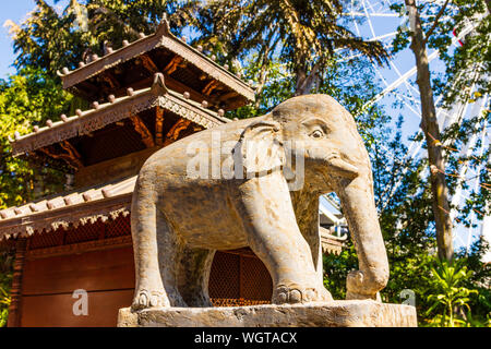 Un elefante in pietra statua fuori la parte anteriore di un tempio. Foto Stock