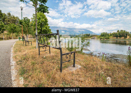 Legno vuota una panchina nel parco affacciato sul lago Viroi in Argirocastro, Albania. Foto Stock
