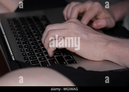 Man digitando su una in bianco e nero e argento tastiera portatile Foto Stock