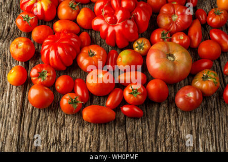 Flat-lay di fresco colorful ripe caduta o Estate cimelio di pomodori varietà su sfondo rustico, vista dall'alto, copia dello spazio. Foto Stock