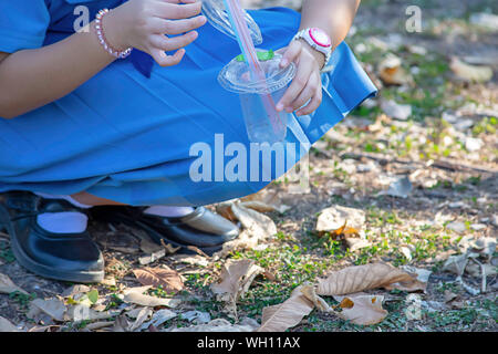 Mano ragazza Asean tenendo un bicchiere di plastica di scarto e di bere cannucce colorate. Foto Stock