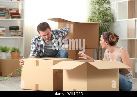 Il marito avente un incidente la sofferenza mal di schiena cercando di sollevare un box moving home Foto Stock