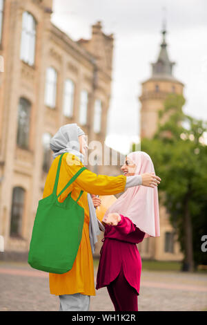 Studente musulmane di indossare il hijab rosa incontro migliore amico Foto Stock