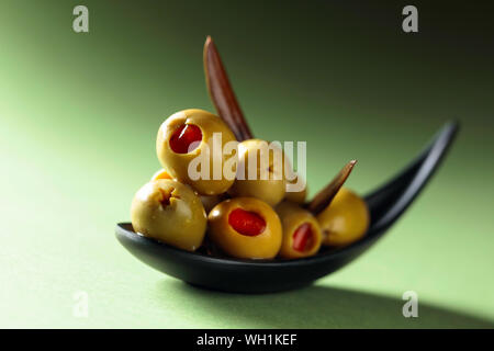 Stuzzicanti Olive farcite con peperoncino rosso in nero piccolo recipiente. Foto Stock