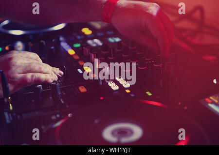 Le mani del concerto di mixaggio dj brani musicali sul palco.disc jockey regolazione del cingolo di frequenza regolatori con il mixer audio di pannello in discoteca.Electronic Foto Stock
