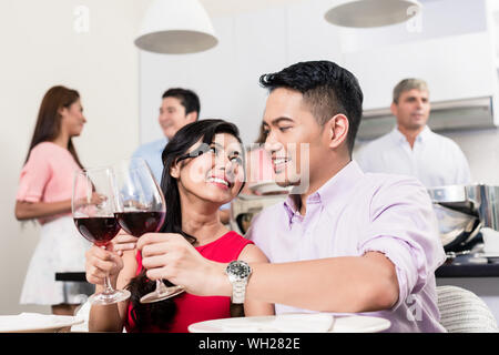 Sorridente coppia giovane tostatura di bicchieri di vino Foto Stock