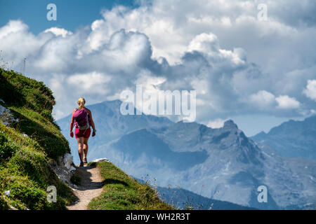 Una donna passeggiate su un sentiero di cresta in alta quota su Dent du Villard vicino a Courchevel nelle Alpi francesi. Foto Stock