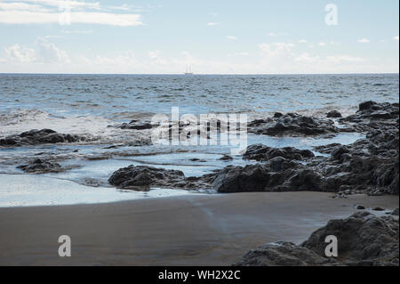 Remote sulla spiaggia vulcanica con tranquilla colpendo onde di sabbia e rocce, in un giorno nuvoloso, dopo la tempesta, sulla costa settentrionale di Tenerife, Spagna Foto Stock