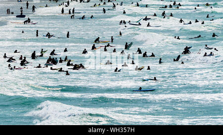 I turisti che si diverte nel mare visto in silhouette a Fistral a Newquay in Cornovaglia.; Foto Stock