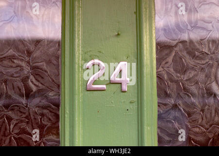 Il numero civico 24 visto su una porta verde con pannelli in vetro Foto Stock