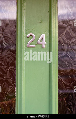 Il numero civico 24 visto su una porta verde con pannelli in vetro Foto Stock