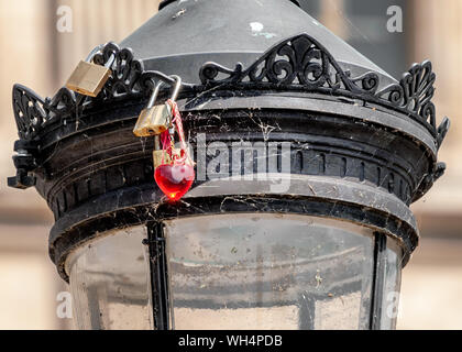 Vecchi lucchetti e un cuore rosso key ring bloccato su un lampione coperto con ragnatela a 'Pont des Arts' ponte pedonale a Parigi. Foto Stock