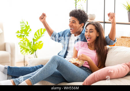 African giovane guardare sport in televisione e rasserenanti squadra preferita Foto Stock