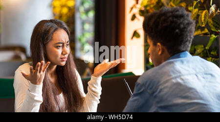 Furious giovane ragazza disperatamente cercando di afro guy Foto Stock