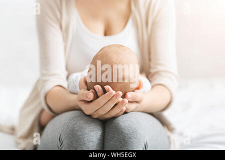 Madre tenendo la testa del suo neonato in mani Foto Stock