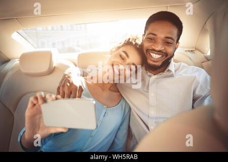 Felice coppia afro tenendo selfie nella nuova vettura Foto Stock