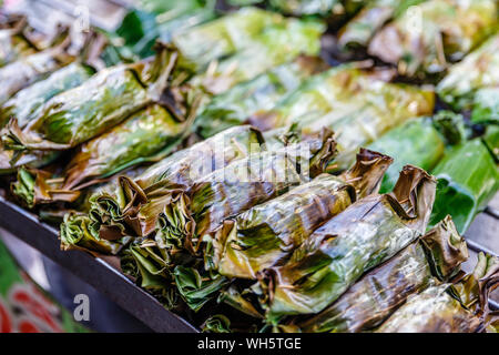 Grigliata di riso con latte di cocco e taro o banana avvolto in foglie di banano. Thai street food, Thai dessert tradizionale. Bangkok, Thailandia Foto Stock