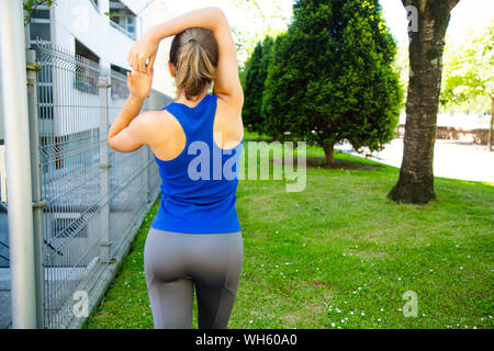 Vista posteriore di una giovane donna attraente facendo esercizi di stretching all'aperto Foto Stock