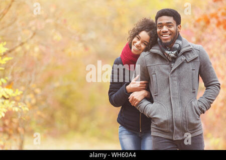 Passeggiata romantica. Afro giovane a piedi attraverso il parco di autunno Foto Stock