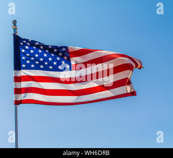 La bandiera americana dispiegarsi in vento sul cielo blu chiaro Foto Stock