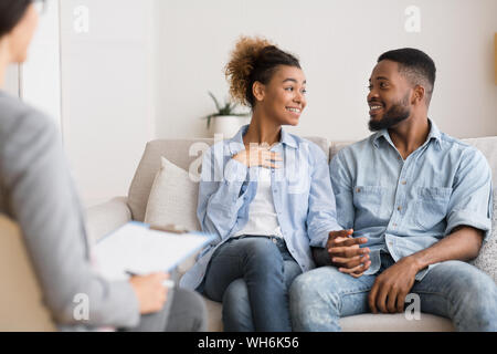 Allegro Afro giovane condividere notizie con terapista coniugale dopo la riconciliazione Foto Stock