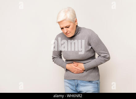 Infelice donna senior holding dello stomaco, che soffrono di dolore addominale Foto Stock