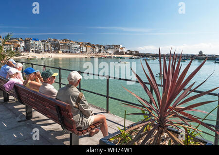 I villeggianti e turisti, persone, visitatori seduta dal porto di st.Ives in Cornovaglia, Inghilterra, Regno Unito. Foto Stock