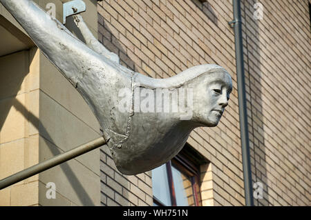 La testa di Attendant scultura appesa sopra le porte alla moderna tenement blocchi nel nuovo Gorbals, Glasgow, Regno Unito Foto Stock