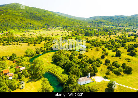 Bellissimo fiume Gacka che scorre tra gli alberi e i campi, summer view, Lika regione della Croazia, drone volando sopra la superficie del fiume Foto Stock