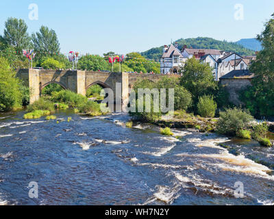 Il veloce che scorre il fiume Dee fluisce attraverso il vecchio ponte di pietra, drappeggiati in bunting e bandiere a Llangollen, Galles Foto Stock