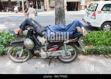 Politica comune in vista della città per vedere Xe Om/ driver moto prendendo un pisolino sul loro moto taxi quando non vi è alcun cliente, Ho Chi Minh City, Vietnam. Foto Stock