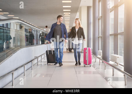 Foto di piedi felici l uomo e la donna che cammina lungo la passerella con le valigie in aeroporto al giorno Foto Stock