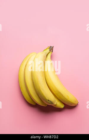 Mazzetto di maturazione banane giallo su sfondo rosa. Vista da sopra. Il cibo la minima nozione. Foto Stock