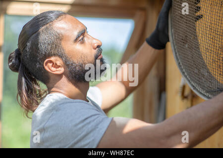 Barbuto giovane uomo prendendo crivello inferiore Foto Stock