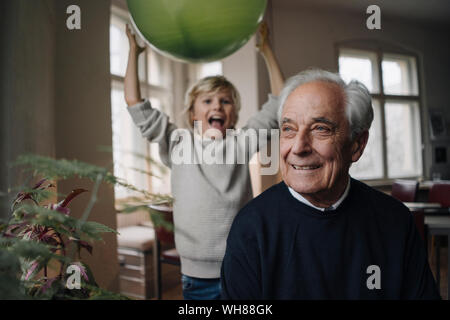 Ritratto di sorridente uomo senior con mio nipote di palloncino di contenimento in background Foto Stock