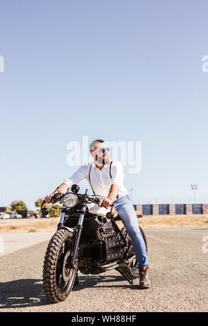 Ritratto di uomo barbuto seduto su una motocicletta Foto Stock