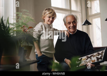 Nonno che mostra collezione di farfalle al nipote a casa Foto Stock