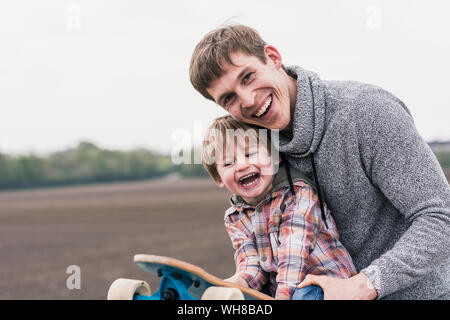 Padre e figlio divertirsi giocando con lo skateboard all'aperto Foto Stock