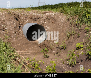 Nuovo di metallo ondulato canale sotterraneo di drenaggio tubo installati nel fosso lungo la strada per agriturismo accesso al campo Foto Stock