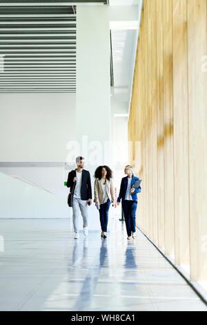 Young business la gente camminare e parlare in un corridoio Foto Stock