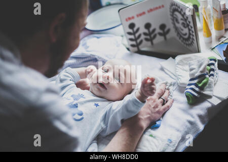 Padre giocando con il suo neonato figlio sulla modifica tabella Foto Stock