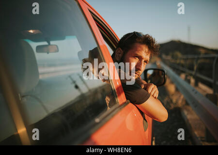 Uomo in un viaggio su strada guardando fuori della finestra auto Foto Stock