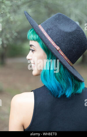 Sorridente giovane donna con tinti di blu e i capelli verdi indossano hat sul giorno di pioggia Foto Stock